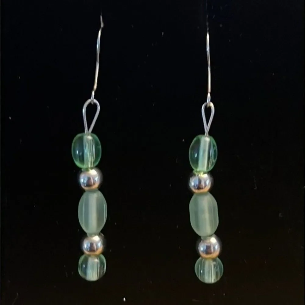 Handcrafted silver tone earrings with green colored beads.
